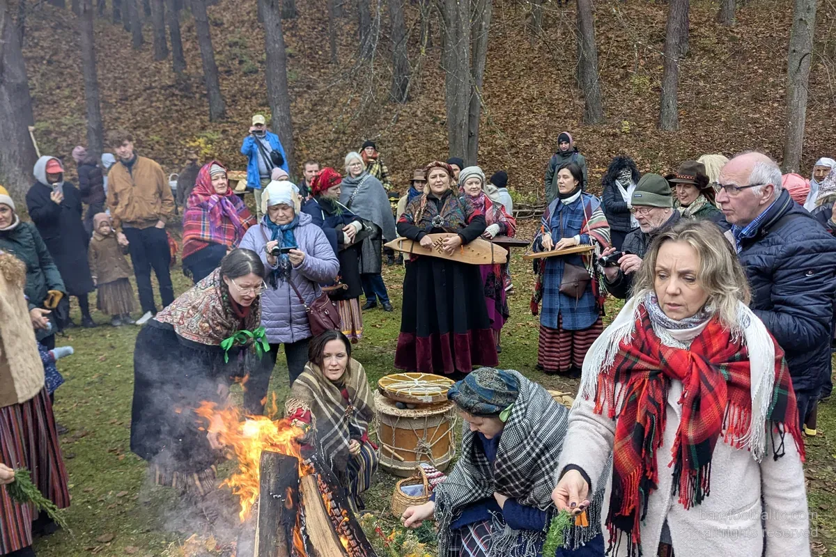 Visitors in folk dress around a Mārtiņdiena bonfire at the Latvian Ethnographic Open-Air Museum, Riga.