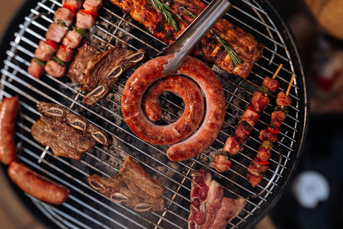 Coiled Latvian sausage, pork ribs, beef short ribs and skewers on a charcoal grill — the cornerstone of Latvian cuisine.