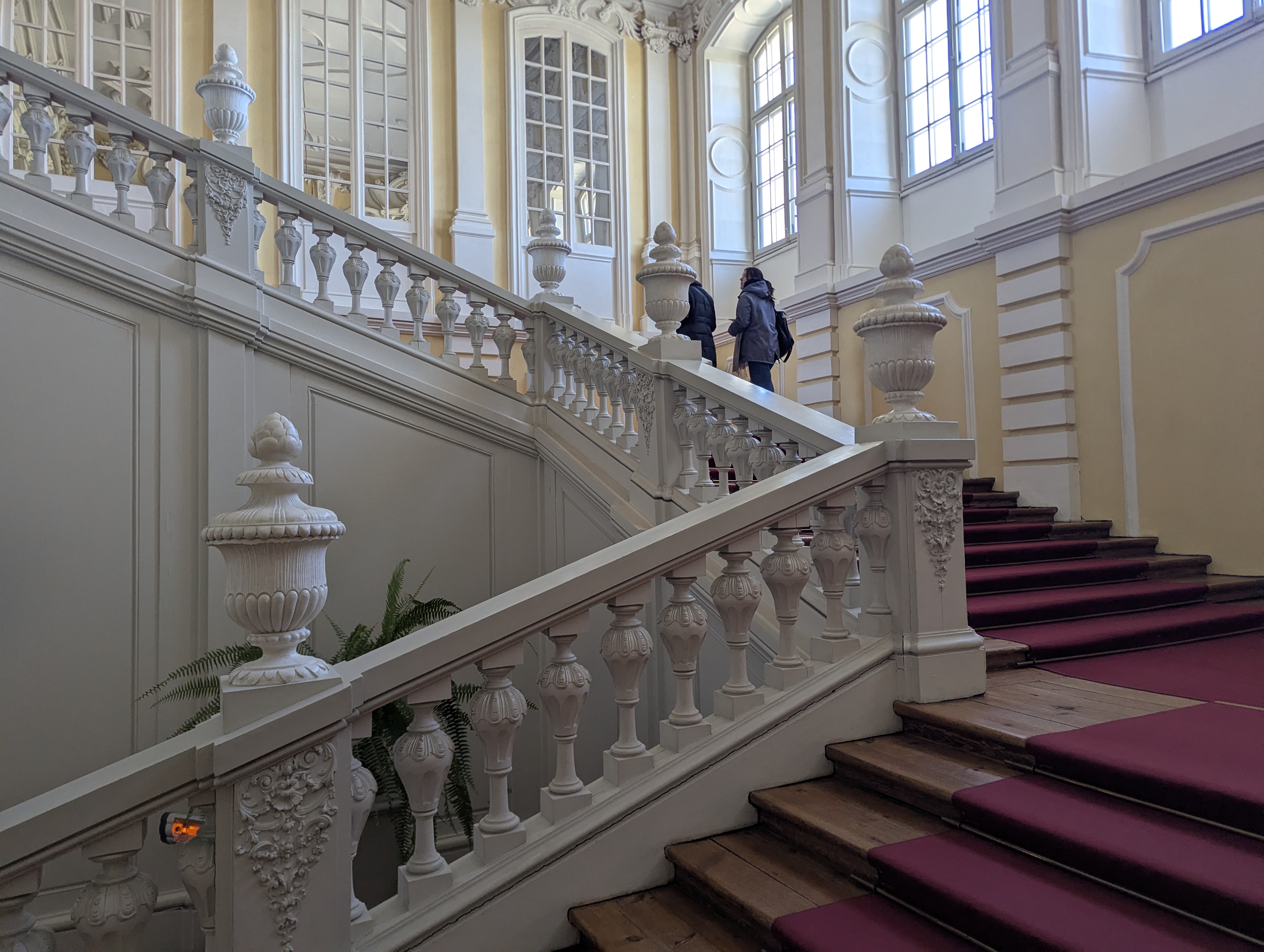 Rundāle Palace state staircase with baroque white-stucco balustrades and burgundy carpet