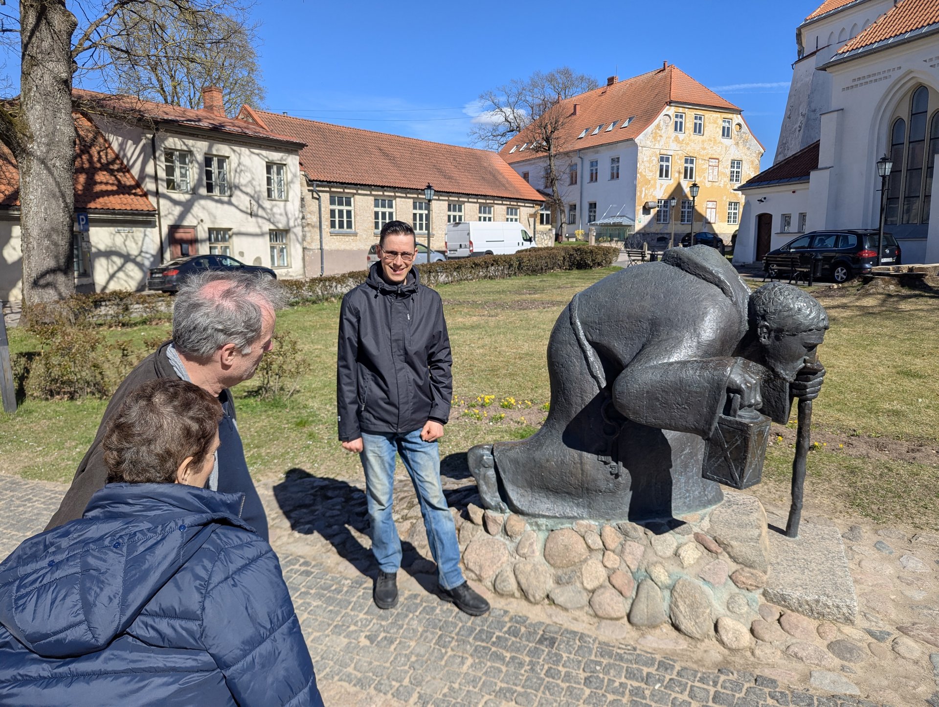 Tour group beside the bronze pilgrim sculpture in Cēsis