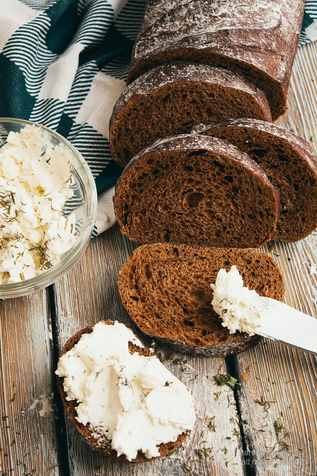 Sliced rupjmaize dark rye bread with a bowl of biezpiens cottage cheese sprinkled with dill