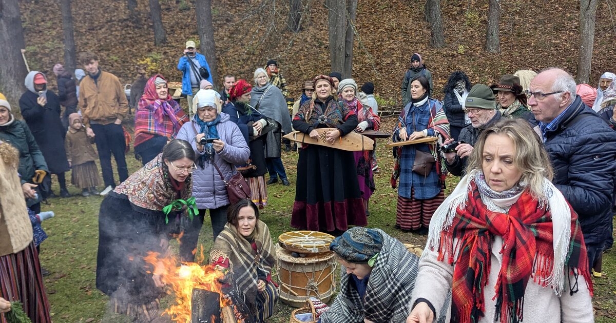 Visitors in folk dress around a Mārtiņdiena bonfire at the Latvian Ethnographic Open-Air Museum, Riga.