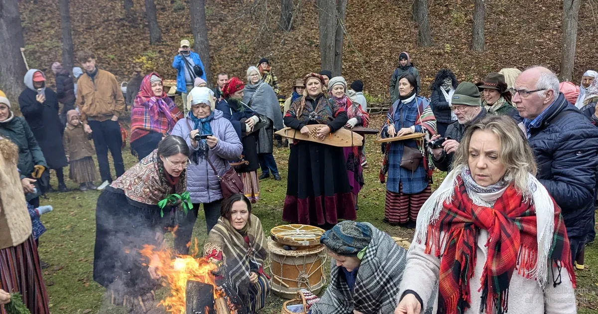 Visitors in folk dress around a Mārtiņdiena bonfire at the Latvian Ethnographic Open-Air Museum, Riga.