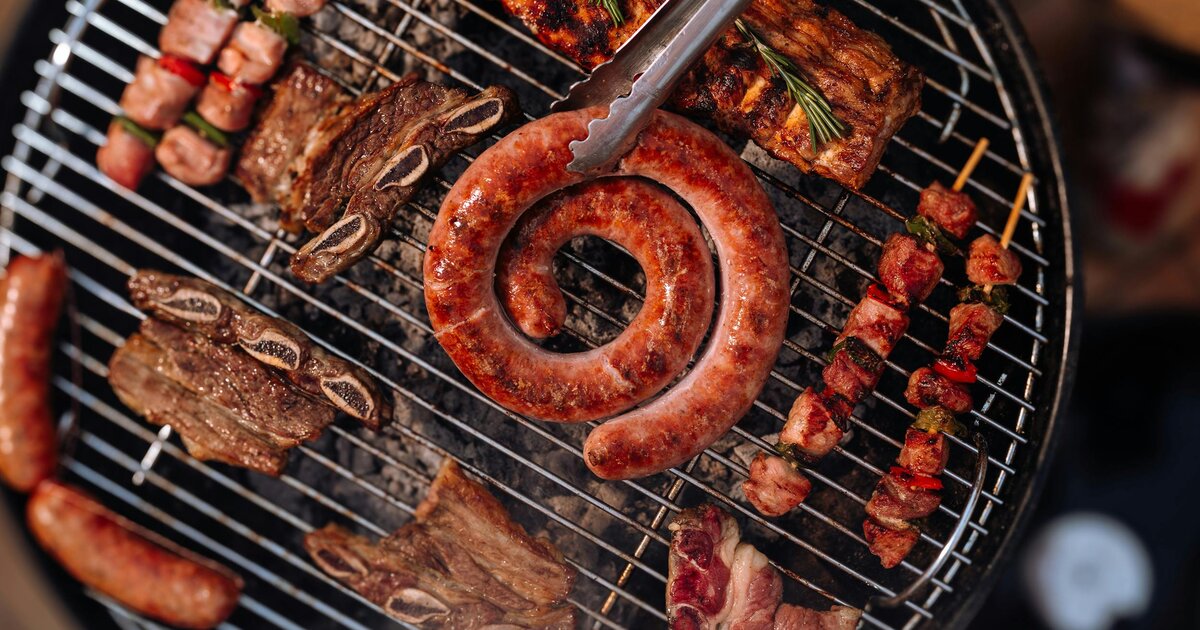 Coiled Latvian sausage, pork ribs, beef short ribs and skewers on a charcoal grill — the cornerstone of Latvian cuisine.